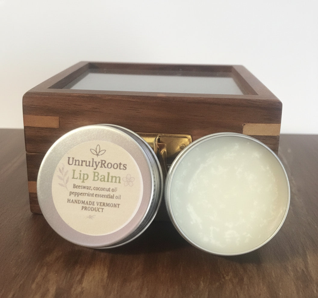 Unruly Roots lip balm in a wooden box on a wooden surface